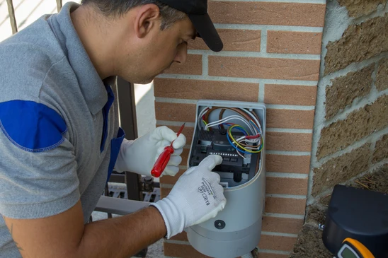 Technicien électricien effectuant la réparation et la programmation d'une fiche technique du moteur d'une porte d'entrée automatique
