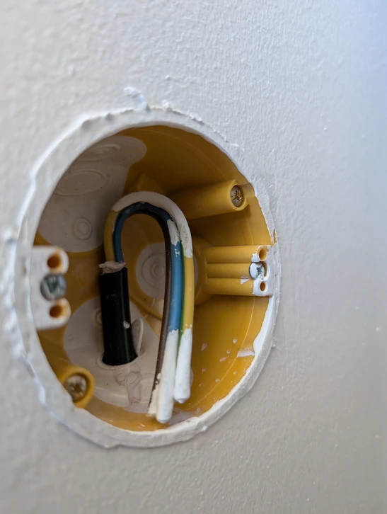 Technicien en combinaison de sécurité et casque blanc travaillant sur installation électrique résidentielle